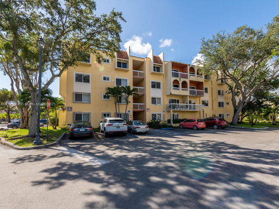 Front view of a multi-story apartment building with parking area.