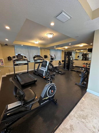 Room with gym equipment including treadmills and exercise bikes.