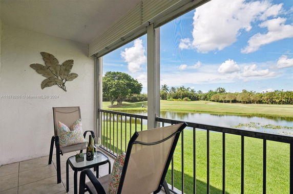 Outdoor patio area with chairs and table, overlooking a golf course and water body.