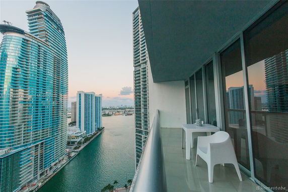 Balcony view from a high-rise building overlooking a river and other modern skyscrapers.