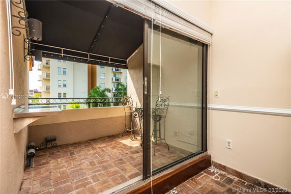 View from an outdoor balcony with brick flooring, metal railings, and a retractable awning.