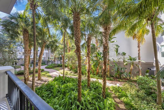View of a tropical garden area with palm trees near a building complex.