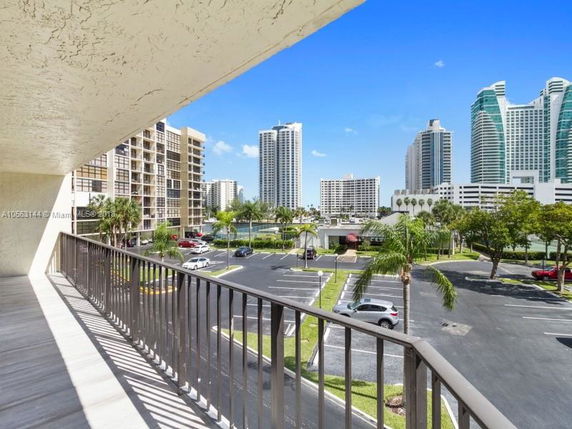 Balcony view overlooking parking area with nearby high-rise buildings.