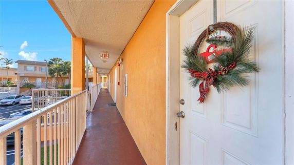Apartment corridor with a decorated door and parking area visible.