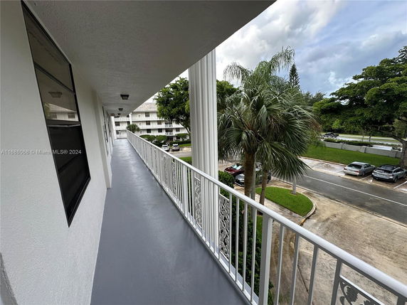 Exterior walkway of a multi-story building with a view of adjacent buildings and parking area.