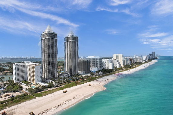 Panoramic view of high-rise buildings along a beachside with ocean in the foreground.