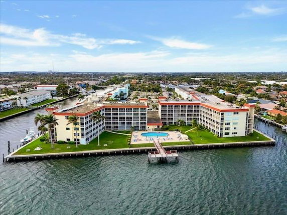 Aerial view of a waterfront multi-story apartment complex with a central swimming pool.