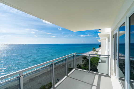 Balcony view of a building overlooking the ocean with a sandy beach below.