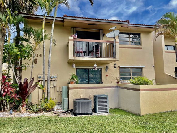 Front view of a two-story residential building with a balcony and garden area.