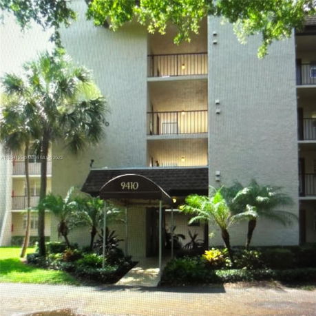 Front view of a multi-story residential building with balconies and entrance canopy.