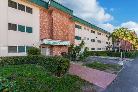 Front view of a multi-story apartment building with brick and cream-colored walls.