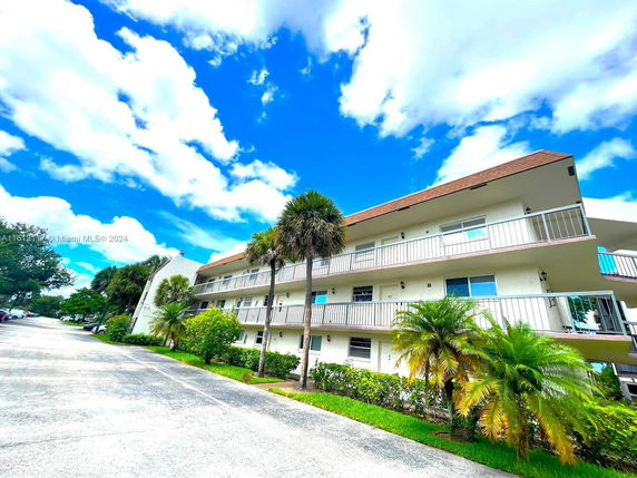 Front view of a multi-story residential building with balconies and a sloped roof.