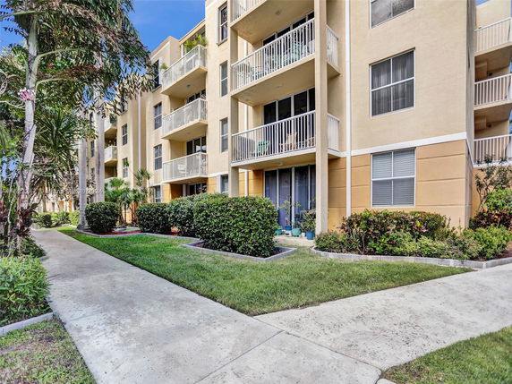 Front view of a multi-story residential building with balconies and landscaped pathways.