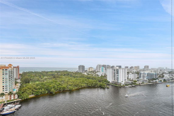 Panoramic view of a coastal cityscape with buildings, greenery, and waterway.
