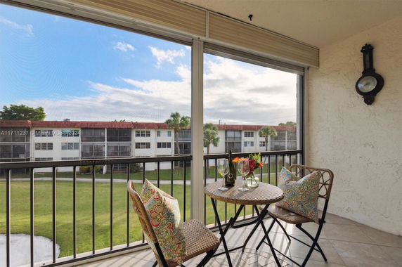Balcony view overlooking enclosed lawn and residential buildings.
