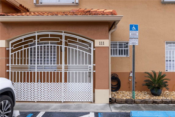 Front view of a building with a gated entrance and designated parking space.