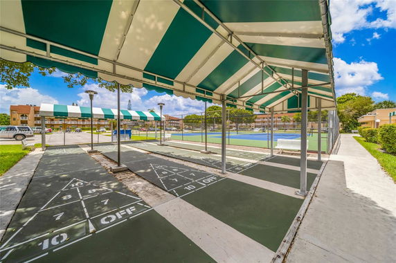Outdoor recreational area with shuffleboard courts and a tennis court.