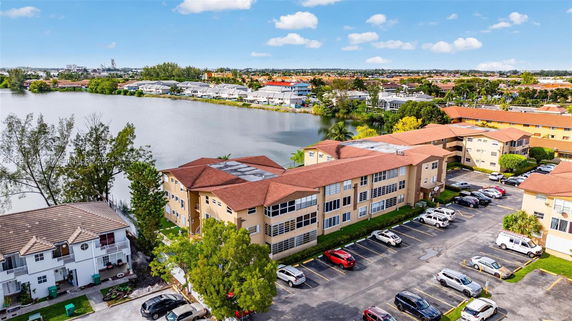 Elevated view of residential buildings near a lake with a parking area.