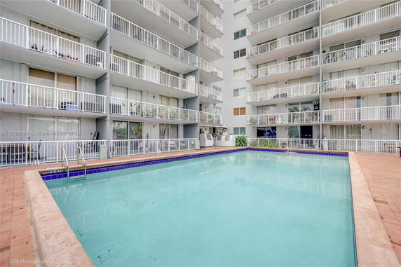 View of a residential building with multiple balconies overlooking a swimming pool area.
