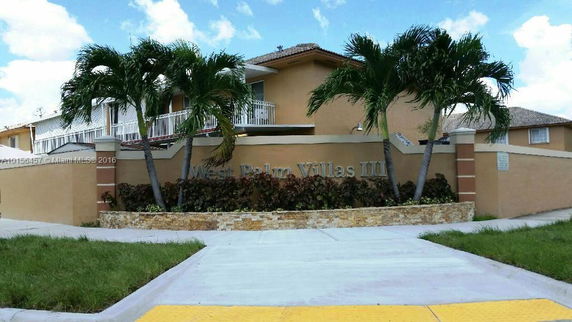 Front view of a two-story building with a sign reading 'West Palm Villas III'.
