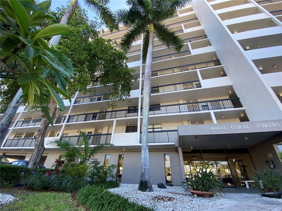 Front view of a multi-story building with balconies and a sign 'Coral Towers'.