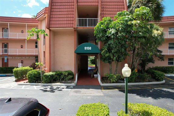 Front view of a building with three stories, featuring balconies and a covered entrance.