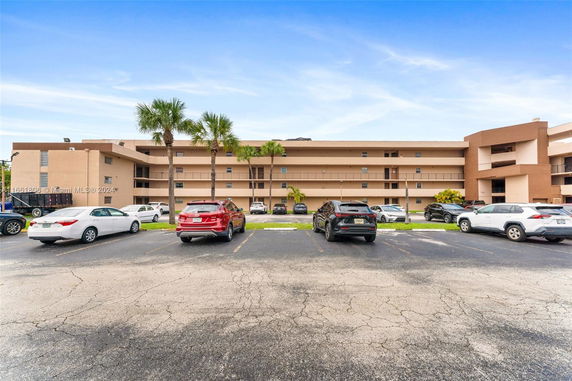 Front view of a multi-story building with a parking lot.