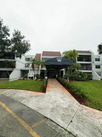 Front view of a multi-story building with a covered entry and surrounding landscaping.