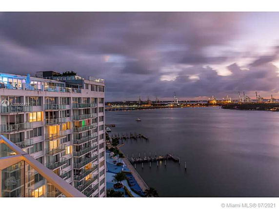 Cityscape view of a waterfront area with a multi-story building and harbor.