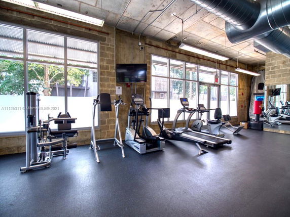 Indoor gym area with exercise equipment and large windows.