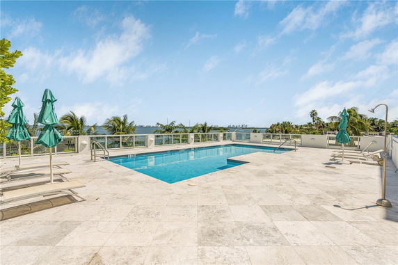 Outdoor swimming pool area with lounge chairs and umbrellas.