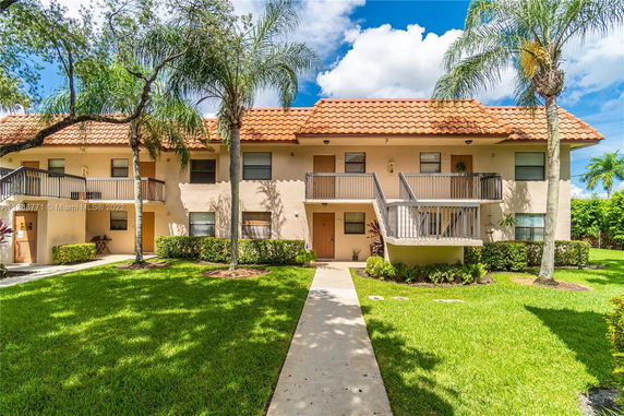 Front view of a two-story residential building with balconies and a tiled roof.