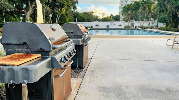 Outdoor swimming pool area with barbecue grills nearby.