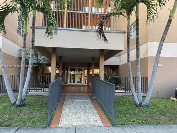 Front view of a multi-story building with a pathway and palm trees.