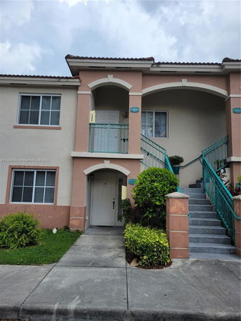 Front view of a two-story house with arched balconies and stairs.