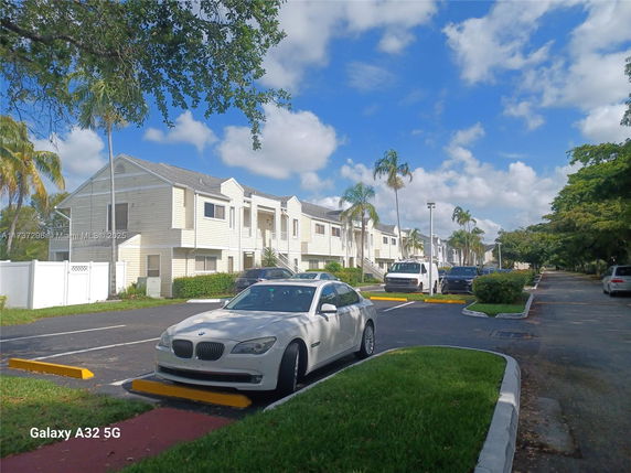 Outdoor view of a parking area in front of a row of multi-story residential buildings.