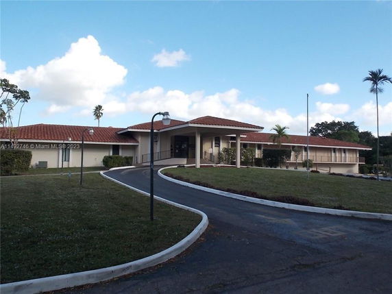 Front view of a single-story building with a red tiled roof and a driveway.