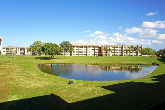 View of a pond with multiple-story buildings in the background.