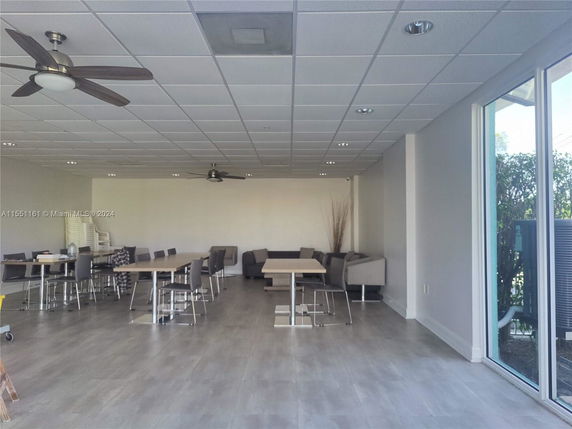 Interior view of a clubhouse with tables, chairs, and ceiling fans.