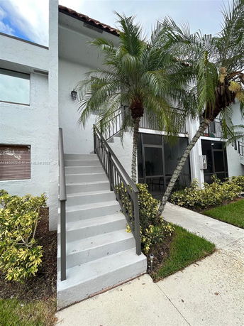 Front view of a two-story building with an exterior staircase and a tiled roof.
