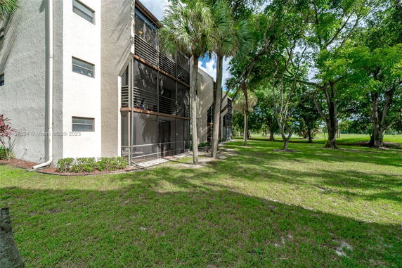 Side view of a multi-story building with screened balconies and trees surrounding it.