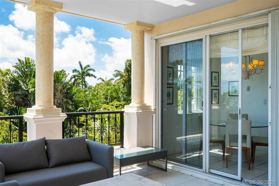 Outdoor patio area with columns and sliding glass doors, overlooking lush greenery.