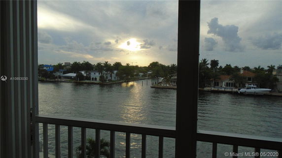 Panoramic view from a building overlooking a waterfront area with houses and trees.