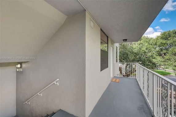 Exterior view of a building hallway with railing and trees in the background.