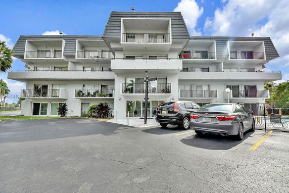 Front view of a multi-story residential building with balconies and parking area.