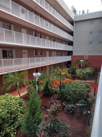 View of a multi-story building corridor with balconies and landscaped garden area.