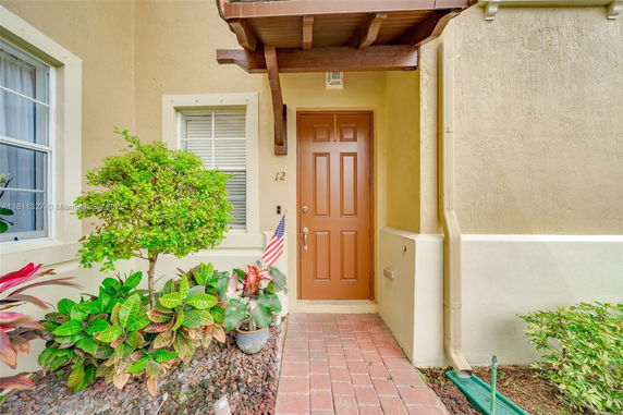Front entrance of a house with a brown door and a window beside it.