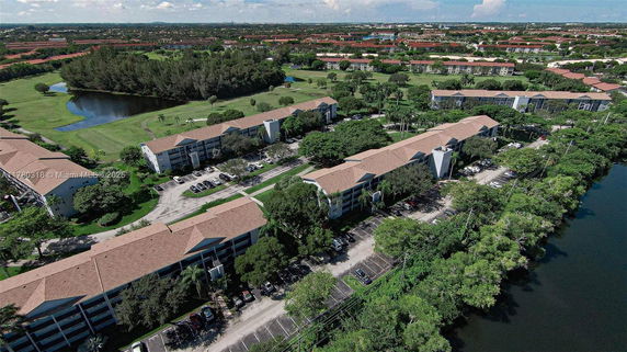 Panoramic view of residential buildings surrounded by greenery and a lake.
