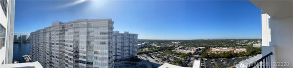 Panoramic view from a high-rise building overlooking surrounding areas including other buildings and parking lots.