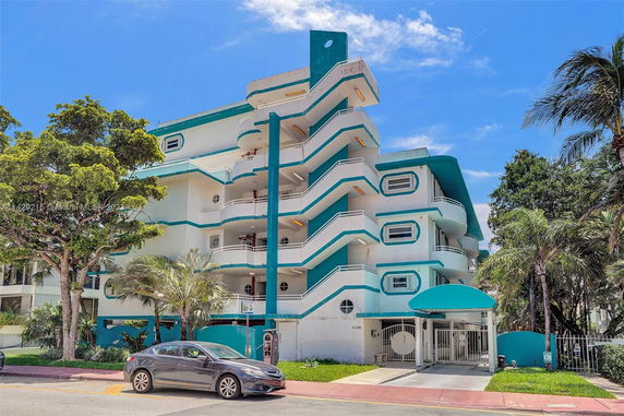 Front view of a multi-story building with balconies and an arched entrance.